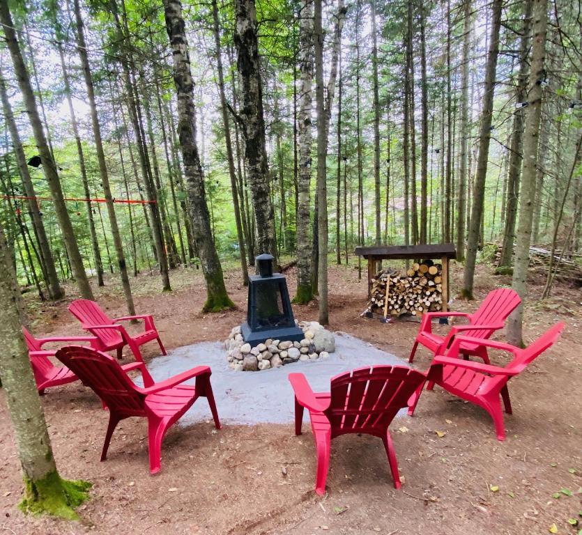 Saint-FaustinCOZY CHALET WELL LOCATED的一群红色椅子和树林里的火坑