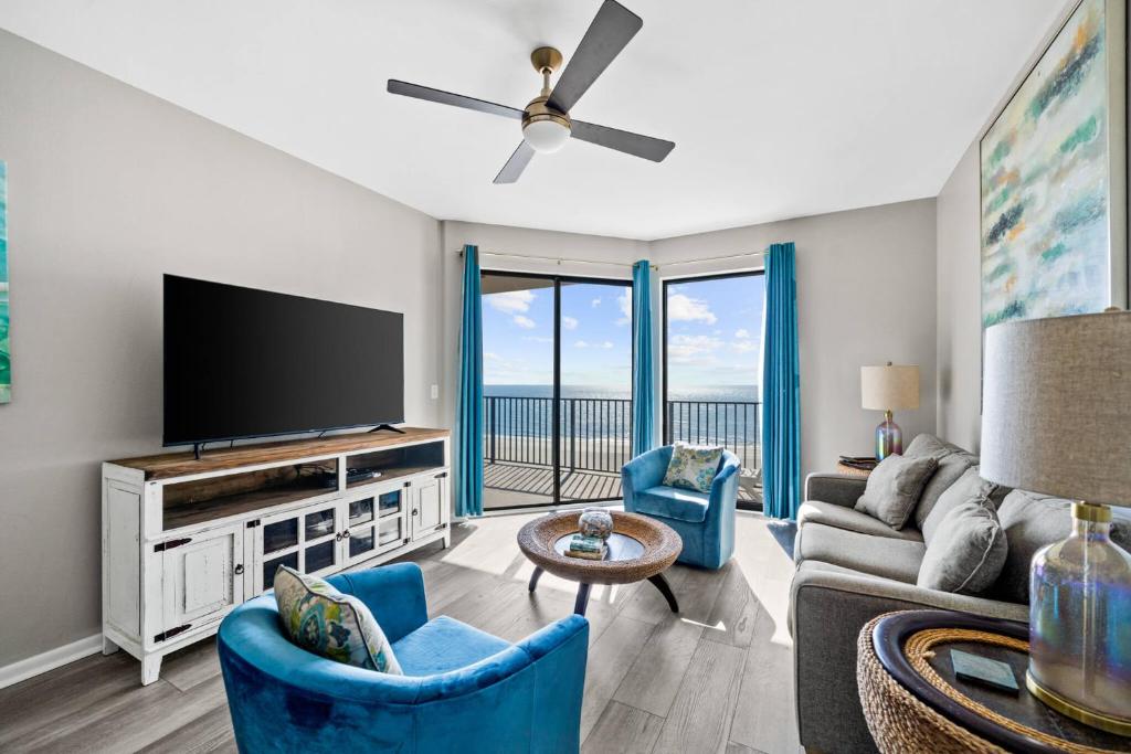 奥兰治比奇Phoenix VII 71113 by ALBVR - Beautiful Beachfront Condo with Amazing Views & Amenities!的客厅配有平面电视和蓝色椅子。