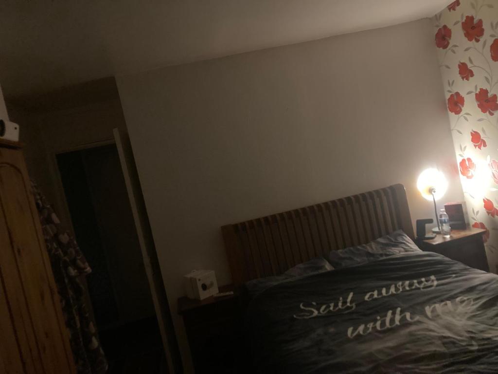哈利伍德Guest House Chelsea的一间卧室配有一张床和一张桌子上的台灯