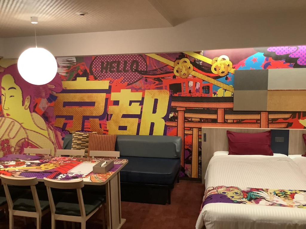 京都MONday Apart Premium KYOTO Station的酒店客房带两张床和一张桌子以及椅子。
