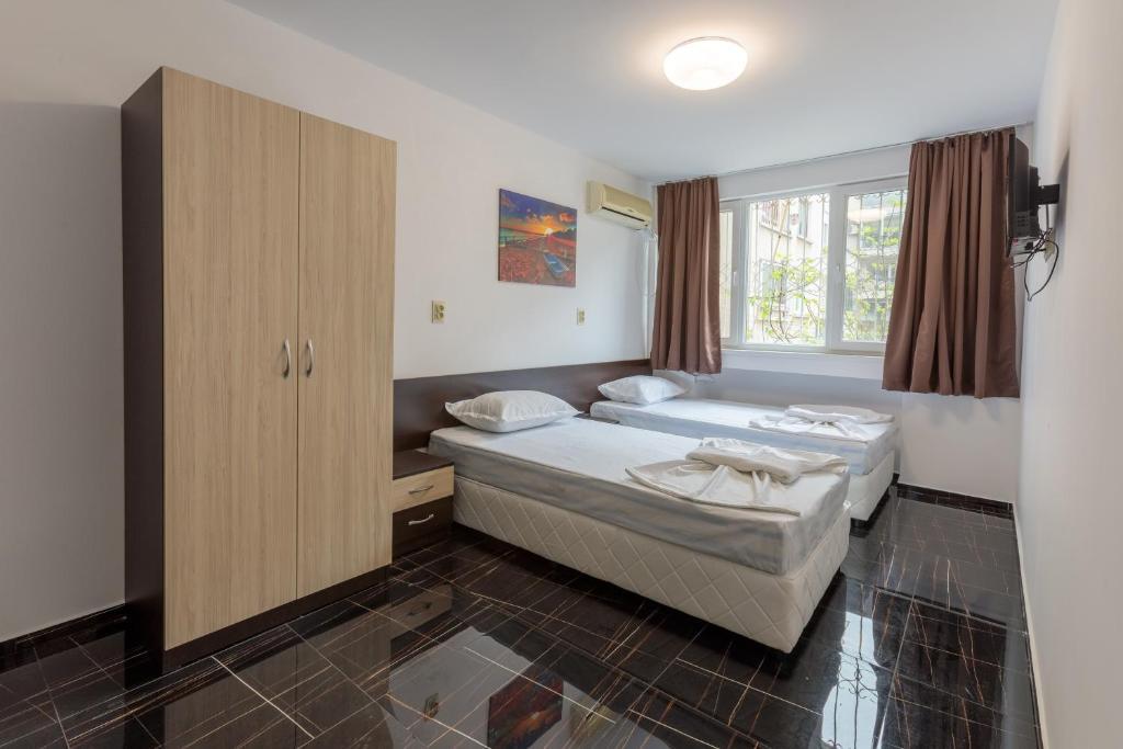 布尔加斯Стаи за гости ПИРОТСКА 39的一间卧室设有两张床、一个橱柜和一个窗口。