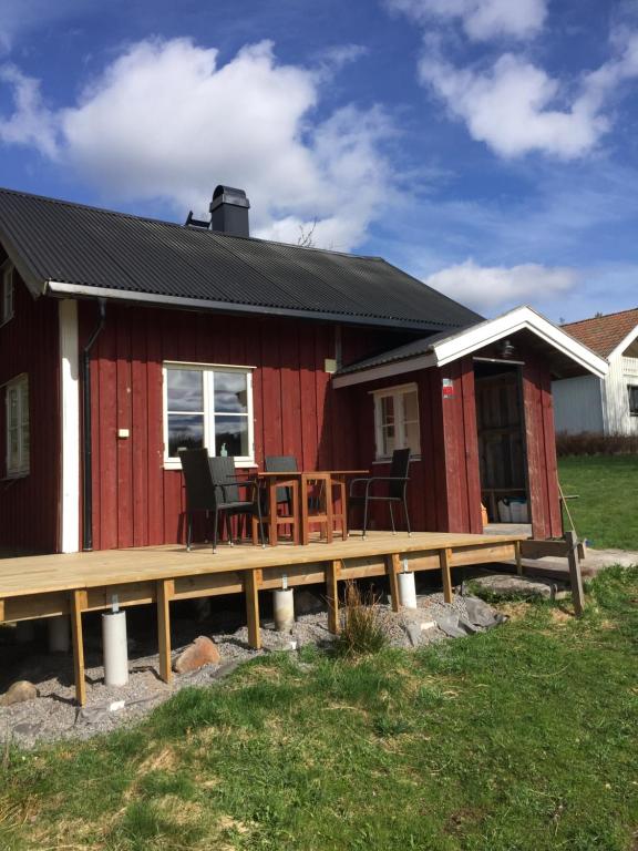 斯特伦斯塔德Stuga vid viltåker nära norska gränsen的红色的房子,设有甲板和桌子