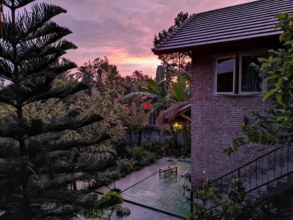 特特巴图Les Rizieres Lombok - Tetebatu的日落前有棕榈树的房子