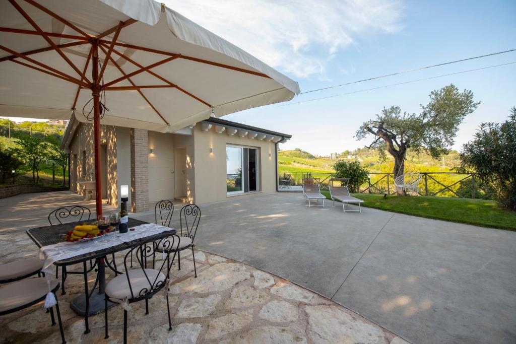 阿夸维瓦皮切纳Dimora Campo delle Mura - Charming House的庭院配有桌椅和遮阳伞。