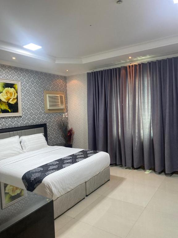 奥朱贝尔Jubail High Rise Hotel的一间卧室配有一张大床和紫色窗帘