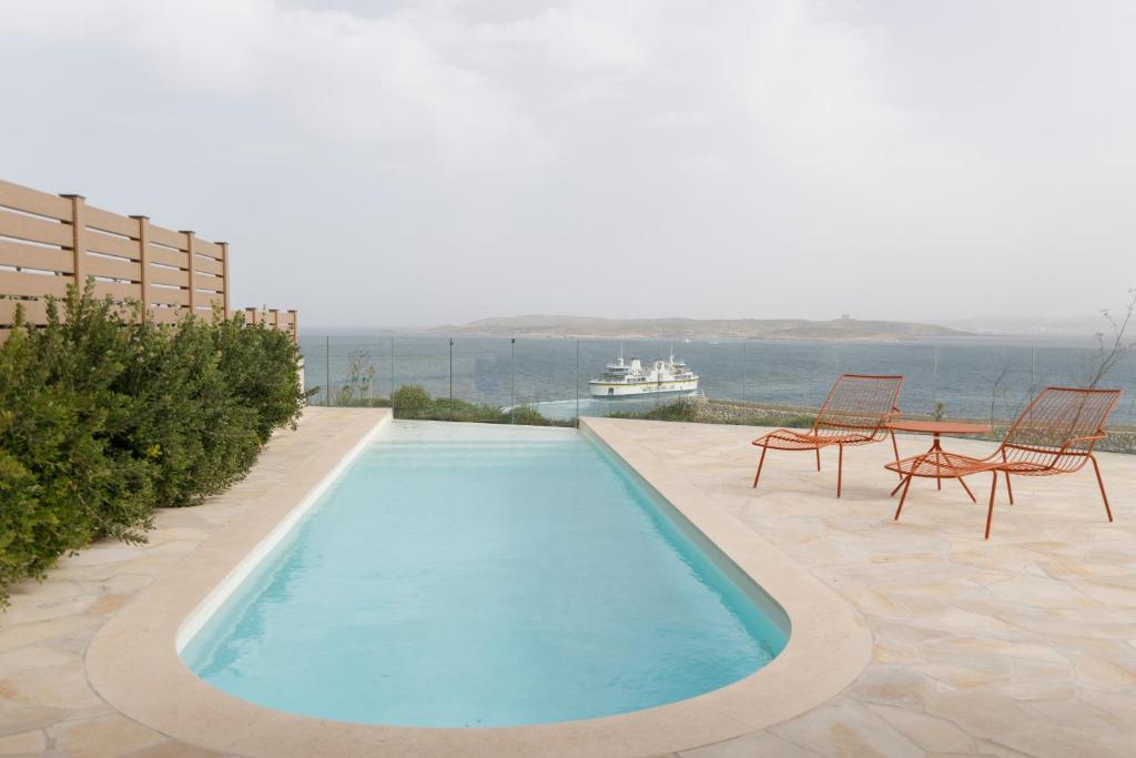 MġarrGozo Harbour Views, Mgarr Heights的一个带两把椅子的游泳池,水中还有一条船