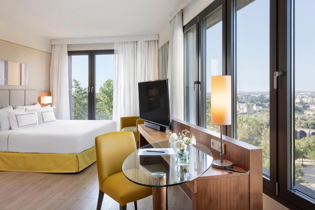 卢森堡卢森堡美利亚酒店的酒店客房设有一张床和一张桌子及一台电视