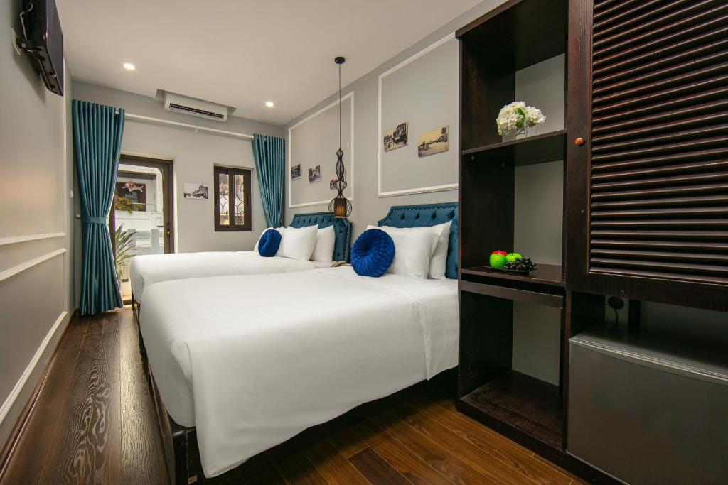 河内La Renta Hotel & Spa的一间卧室配有两张带蓝白色枕头的床