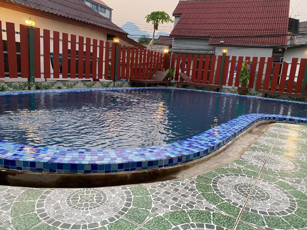 万荣Premier Vang Vieng Hotel的一座带马赛克地板和房子的游泳池