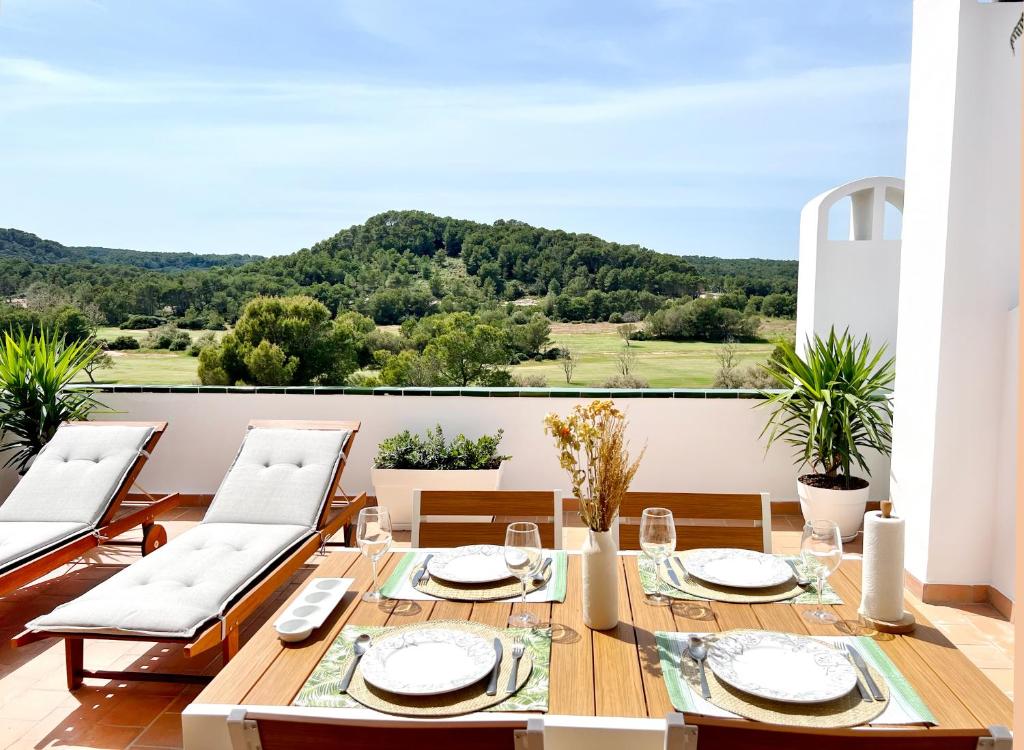 桑帕克Apartamento Atardecer en Menorca Son Parc Vista al campo de golf的阳台的用餐室配有桌椅