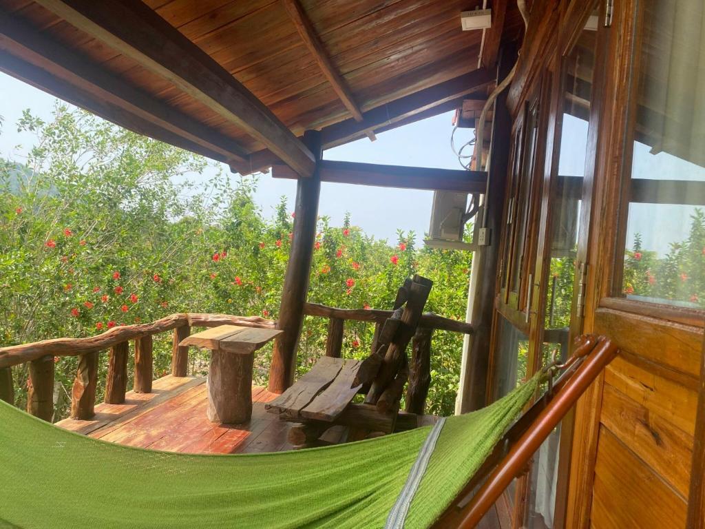 吉仙Ngọc Tiên Farmer Eco Lodge Cat Tiên的小屋门廊上的吊床,鲜花盛开