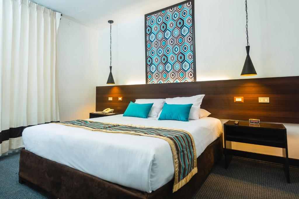 库斯科SACHA Centric的酒店客房配有一张带蓝色枕头的大床