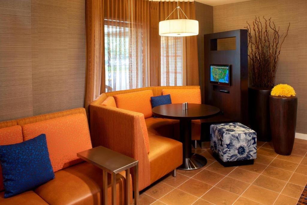 米德尔堡海茨克利夫兰机场南庭院酒店的客厅配有橙色椅子和桌子