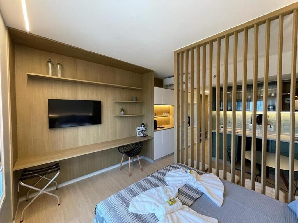 戈亚尼亚Suíte Luxuosa com cozinha Blend Smart 1356的一间卧室配有一张床、一张书桌和一台电视。