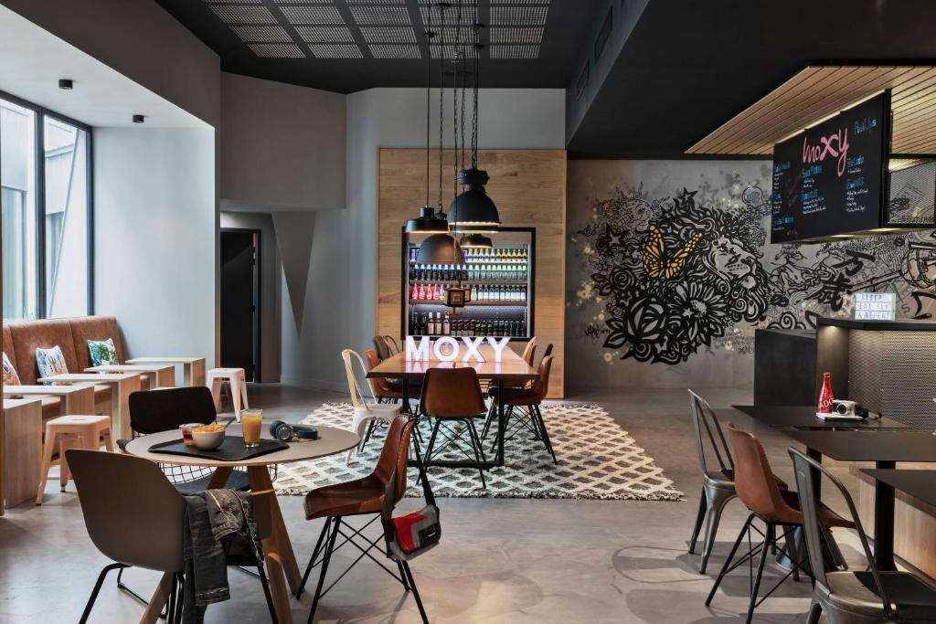 圣艾修伯里Moxy Lyon Airport的餐厅设有桌椅和提供菜单的墙壁