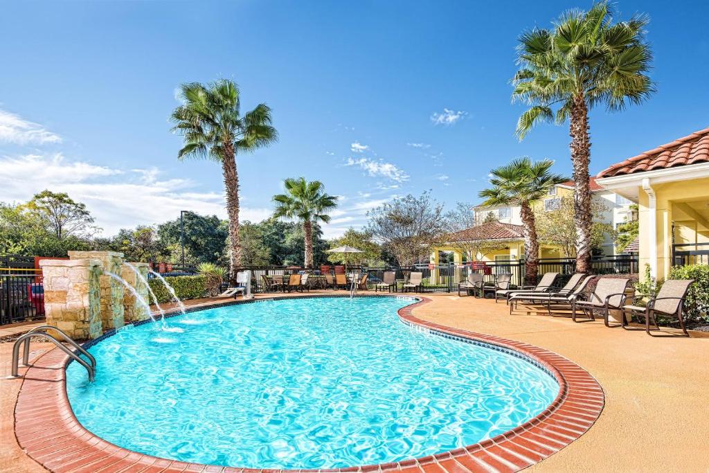 圣安东尼奥圣安东尼奥西北万豪广场套房酒店的一个带瀑布和棕榈树的游泳池
