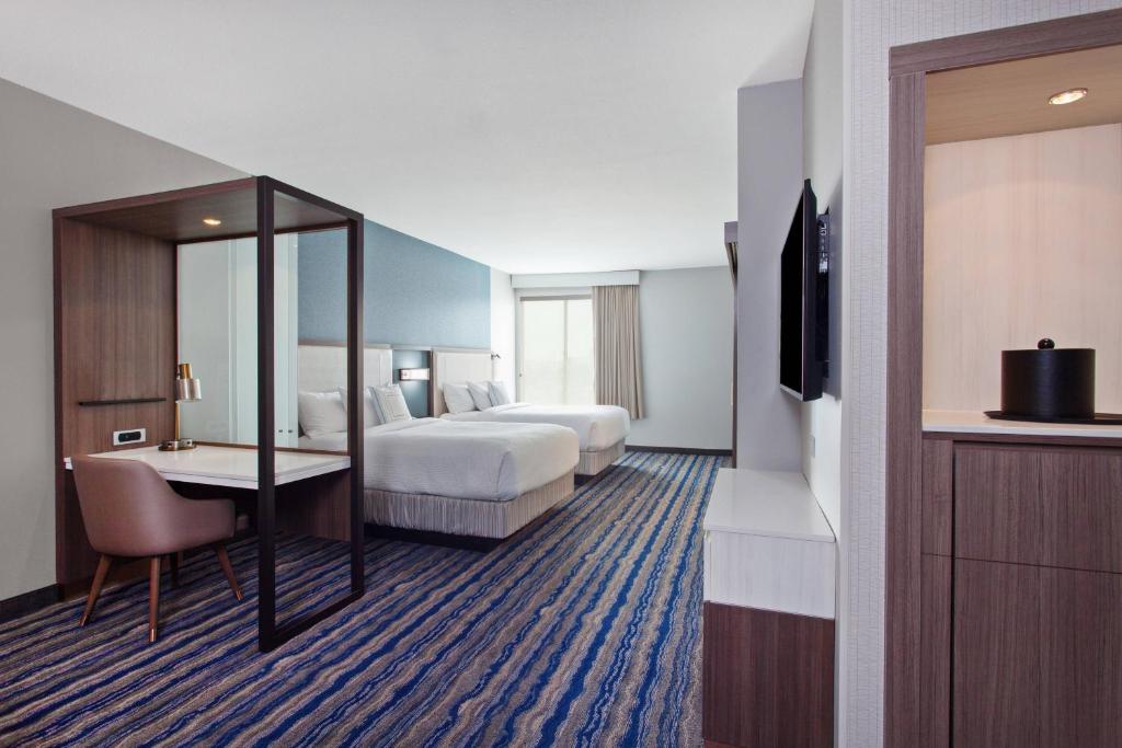 亨廷顿海滩万豪亨廷顿海滩奥兰治县春丘套房酒店的酒店客房设有两张床、一张桌子和一台电视。