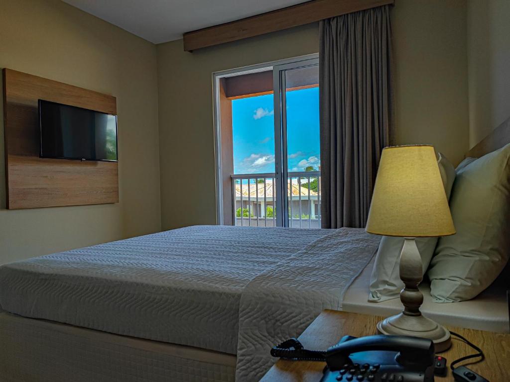 塔曼达雷Hotel Coral Beach的一间卧室配有一张带窗户和灯的床