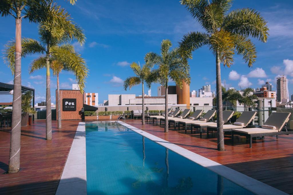 若昂佩索阿LS Hotel的一座带躺椅和棕榈树的游泳池