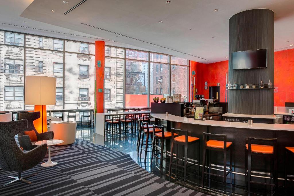 纽约纽约曼哈顿/中央公园万豪万怡酒店的大堂设有拥有橙色墙壁和窗户的酒吧