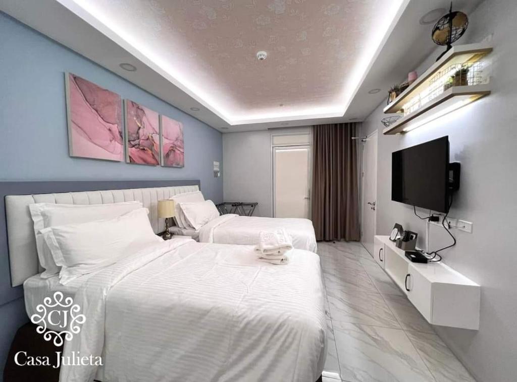 达沃市Casa Julieta Boutique Hotel的酒店客房设有两张床和一台平面电视。