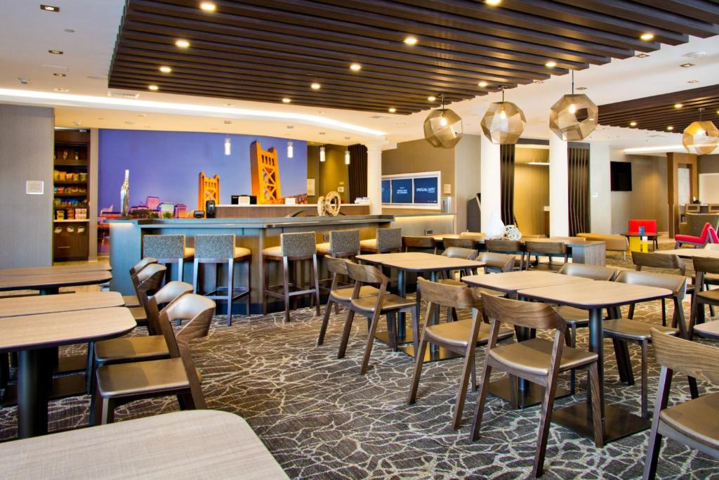 西萨克拉门托SpringHill Suites by Marriott West Sacramento的一间带桌椅的餐厅和一间酒吧