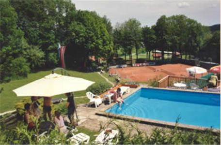 克雷姆斯明斯特Hotel Pension Stadlhuber Aktivpark Kremsmünster的一个带遮阳伞的游泳池,周围的人坐在游泳池周围