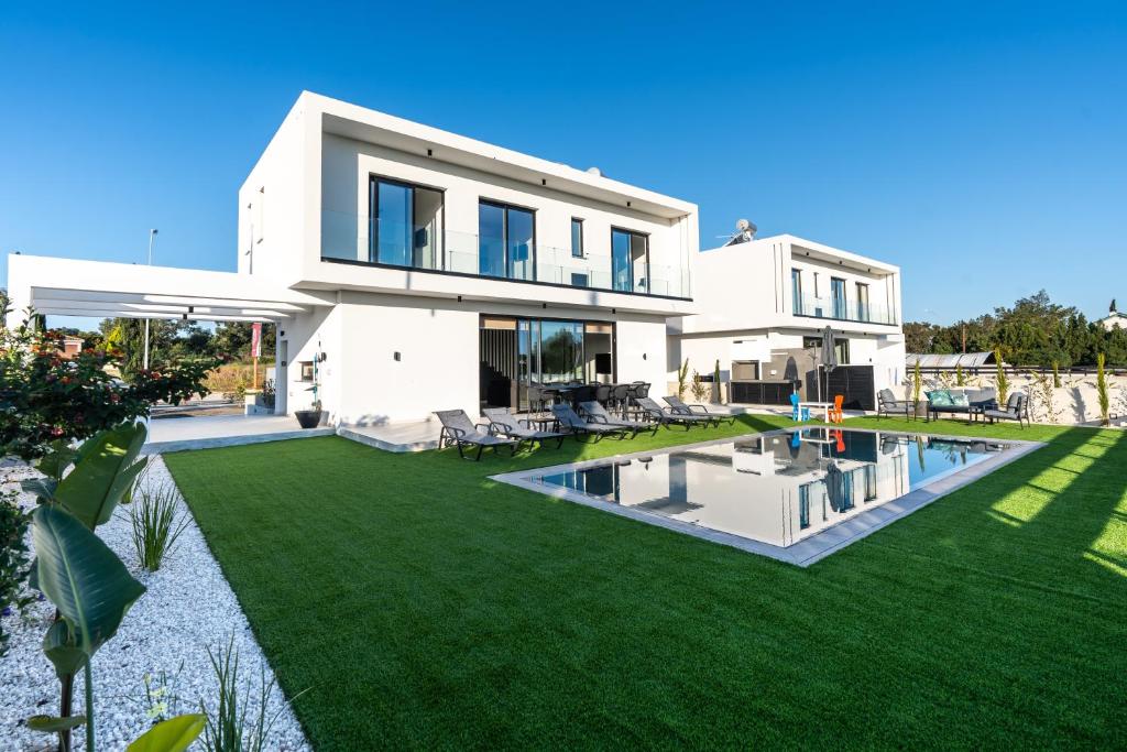 普罗塔拉斯Tsiolakki Homes Luxury Villas的一座带游泳池的庭院的白色大房子