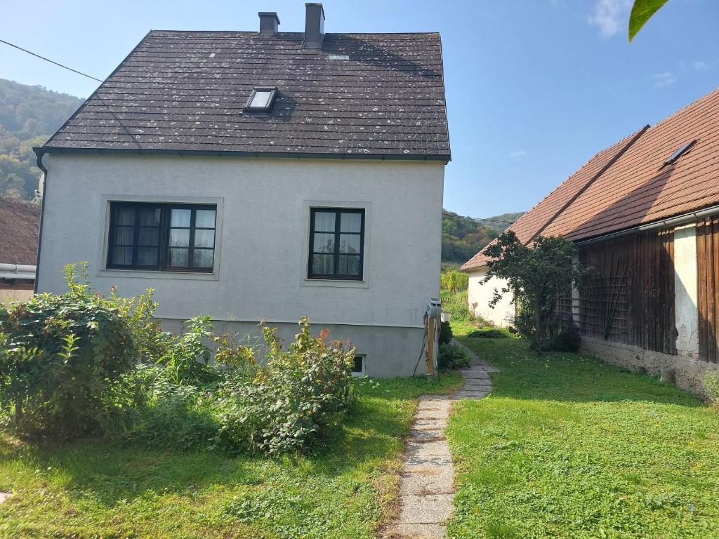 RossatzbachFerienhaus in der Wachau的一间白色的房子,有黑色的屋顶和院子