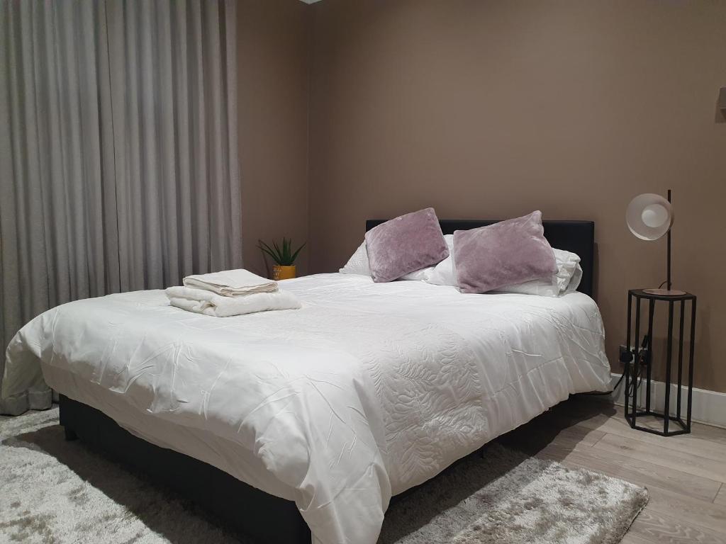 滨海绍森德The Westcliff Room的一间卧室配有一张大床,提供白色床单和紫色枕头