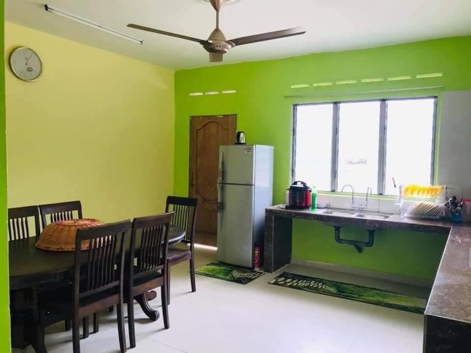 大港Hijau Homestay的一间厨房和带绿色墙壁的用餐室