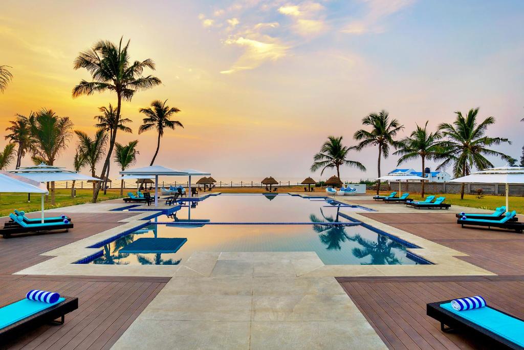 马哈巴利普拉姆Welcomhotel by ITC Hotels, Kences Palm Beach, Mamallapuram的一个带椅子和棕榈树的游泳池以及大海