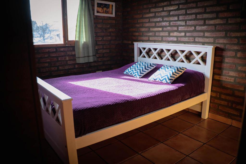 埃博森Cabaña Los Lúpulos的一间卧室配有一张带紫色床单和枕头的床。