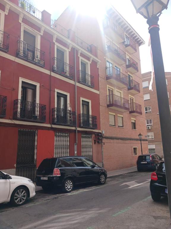 马德里Habitación en Madrid的两辆汽车停在大楼前