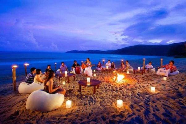 科尔瓦Colva Beach Samaira GuestHouse & Apartments的一群人坐在海滩上,拿着点燃的蜡烛