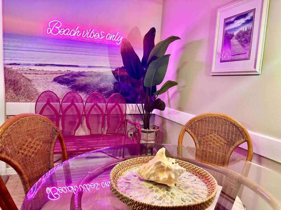 巴拿马城海滩Sandcastles and Sunshine - Gulf Highlands Beach Resort的一张桌子和椅子,墙上有一个紫色的标志