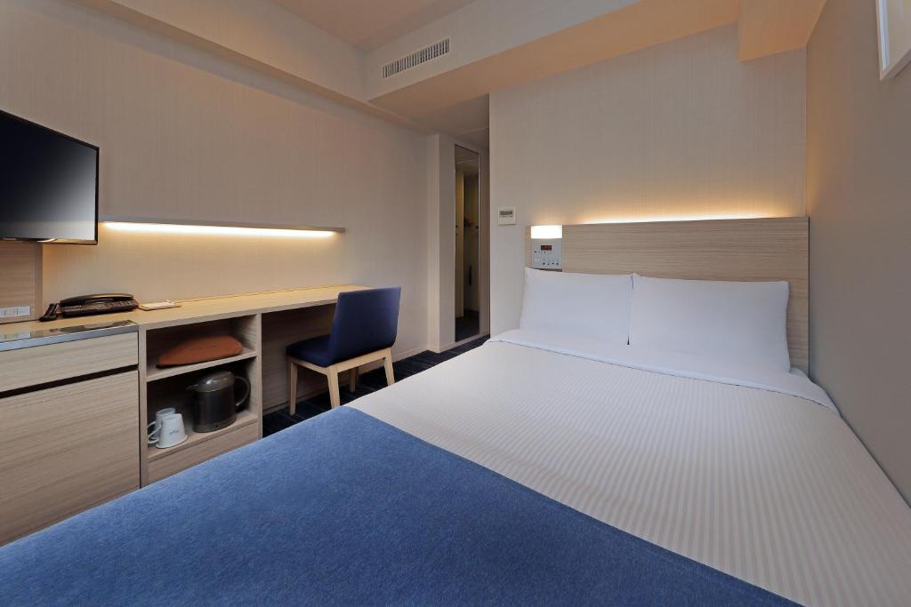 东京Keio Presso Inn Gotanda的酒店客房设有一张大床和一张书桌。