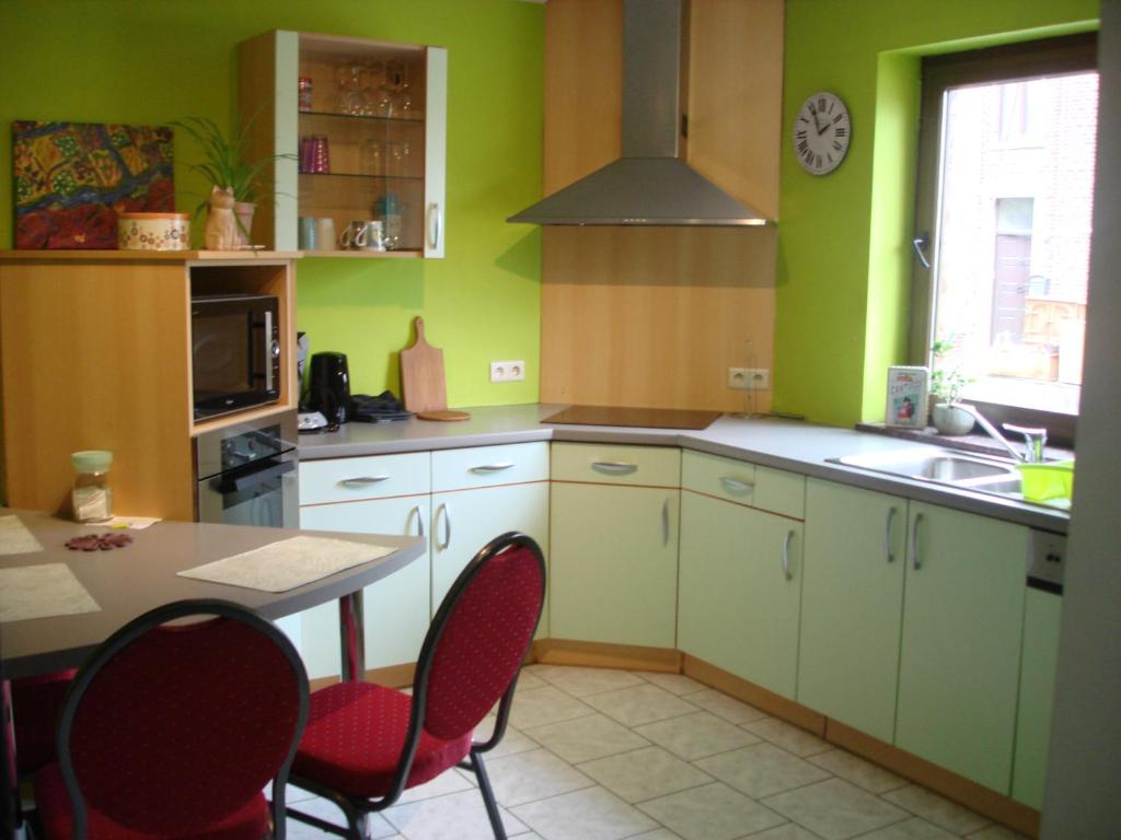 Courcellesappartement Courcelles的厨房设有绿色的墙壁和桌椅