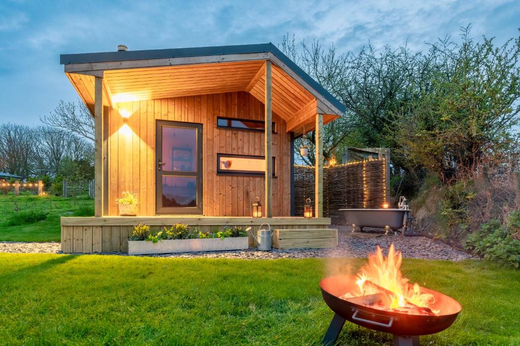 特鲁罗Luxury Glamping Cabin with Outdoor Bath on Cornish Flower Farm的院子里有火坑的小房子