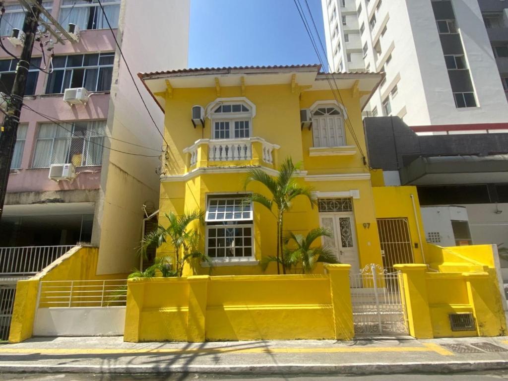 萨尔瓦多Sunflower Hostel的棕榈树前方的黄色房子