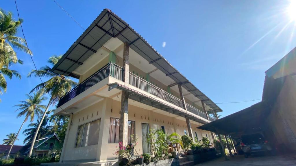 DukuPenginapan Malompek Syariah的带阳台和棕榈树的建筑