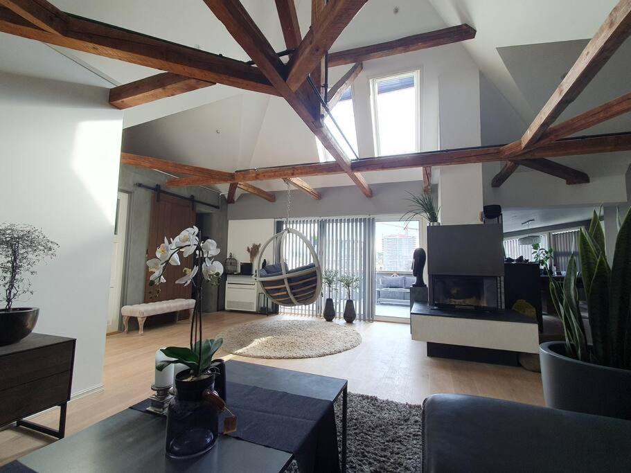 腓特烈斯塔Modern loftsleilighet的一间带木制天花板的客厅和一间带桌子的客厅。