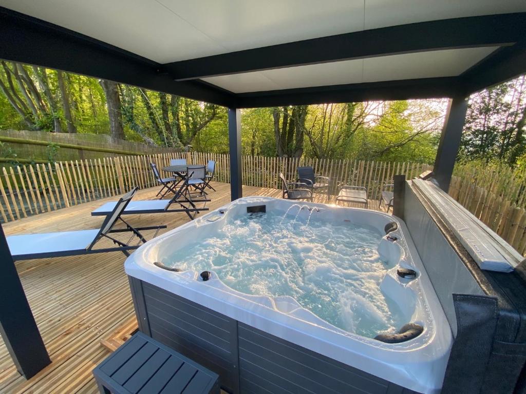 AblonDomaine du Gros Chêne - terrasses avec jacuzzis privatifs的甲板上的热水浴池配有桌椅