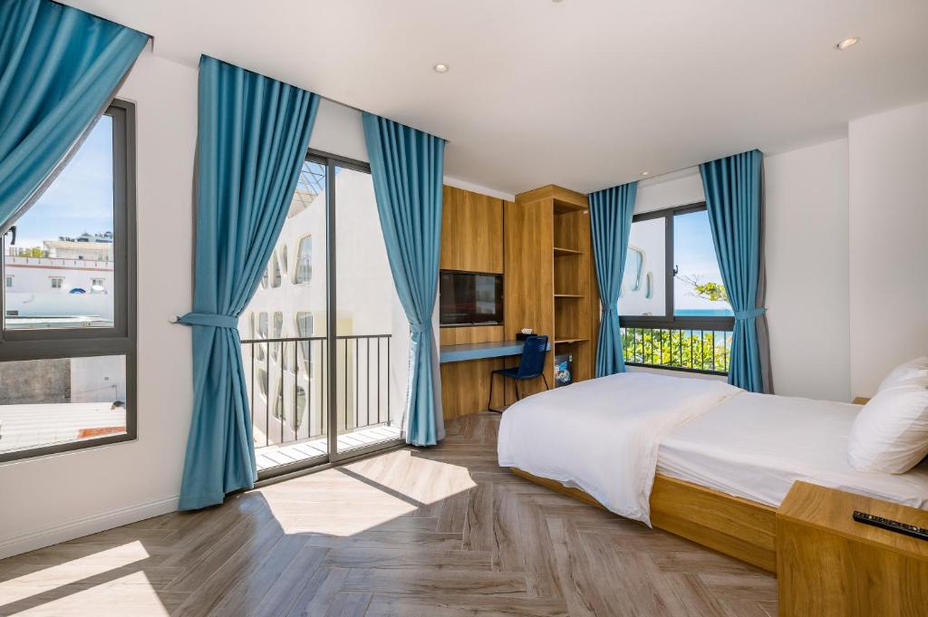 富国Cát Lợi Phú Quốc Hotel的一间卧室配有蓝色窗帘和一张带大窗户的床