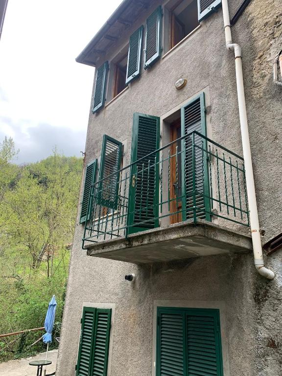 Pian dʼOrsinaCasa Piglione的一座带绿色百叶窗和阳台的建筑