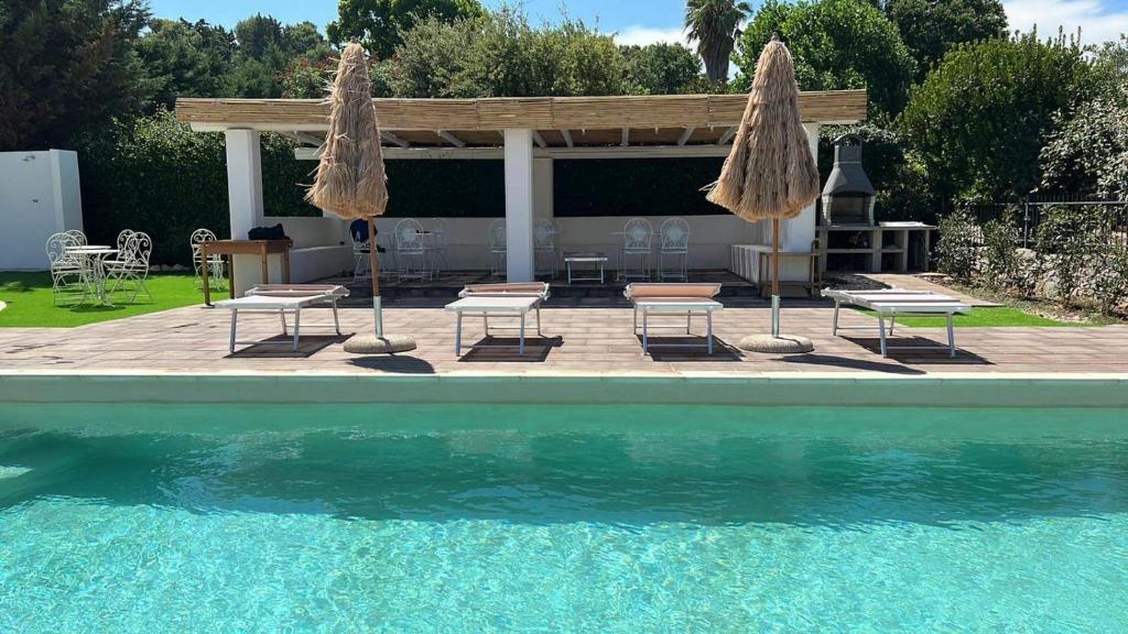 塞尔瓦迪法萨诺Oltre la Vite的一个带两把遮阳伞和椅子的游泳池和一个庭院