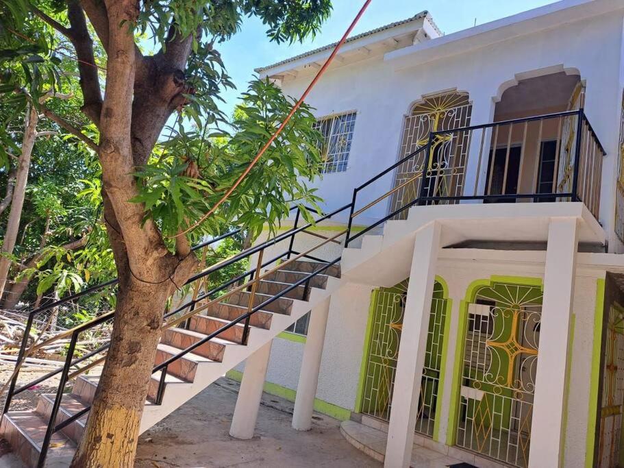 特雷热比奇Mango tree Oasis的一座白色的建筑,有楼梯,位于树旁
