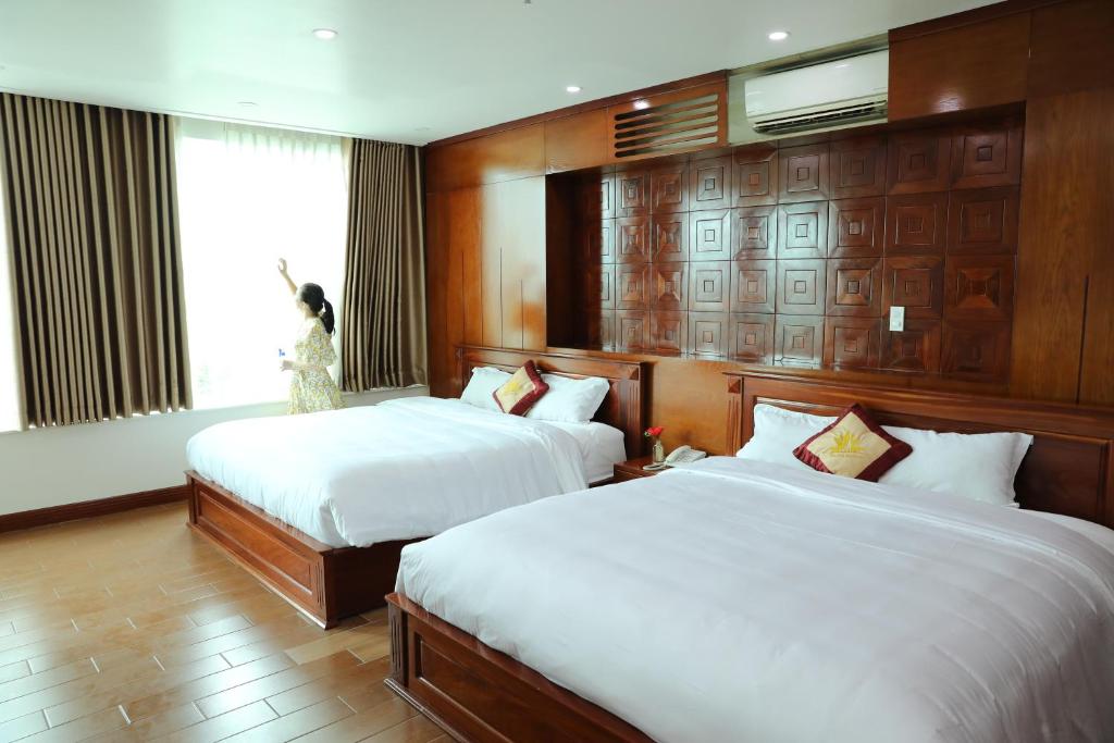胡志明市Thành Vinh Hotel的酒店客房设有两张床和窗户。