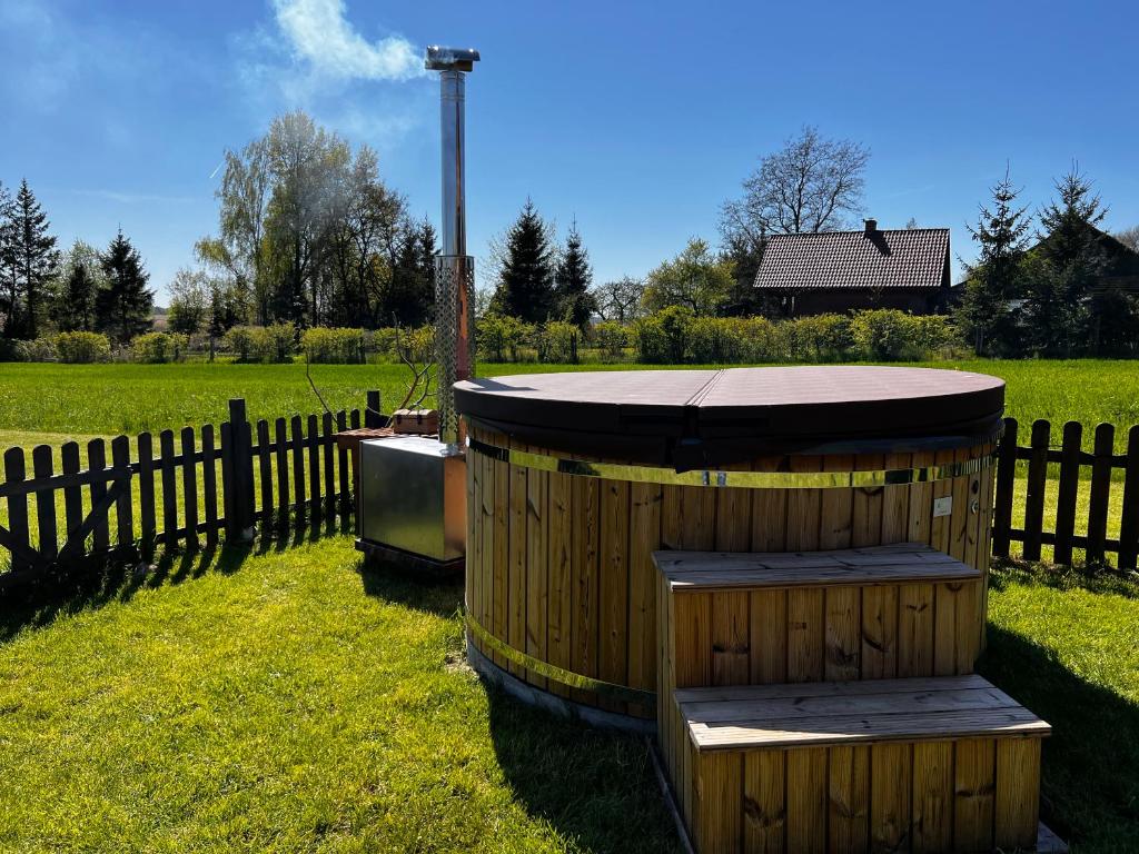 ŁapyŚwierkowy Domek pod Aniołem的围栏旁的草地上木头浴缸