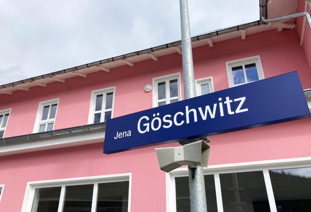 耶拿Hotel Gleis 3viertel Jena的粉红色建筑前的蓝色街道标志